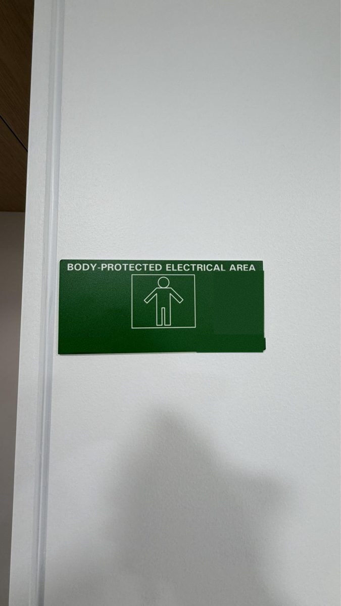 Green body-protected area sign at a treatment room door with a test label